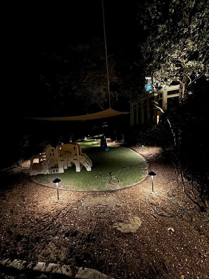 Children's play area with shade sail and path lighting
